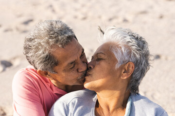 Naklejka premium Affectionate multiracial senior couple kissing on lips while enjoying sunny day at beach