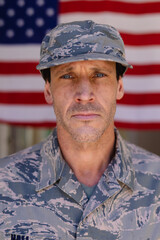 Portrait of confident army soldier wearing cap and camouflage uniform against usa flag