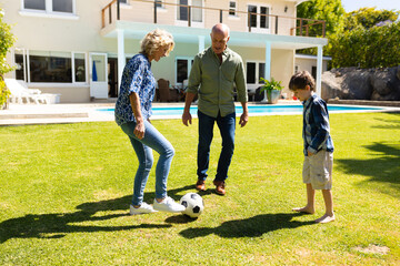 Caucasian grandparents and grandson playing football together in the garden