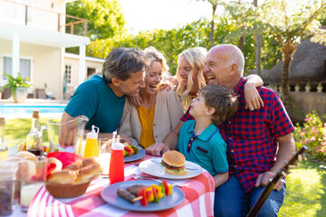 Cheerful caucasian three generational family laughing while sitting together in garden