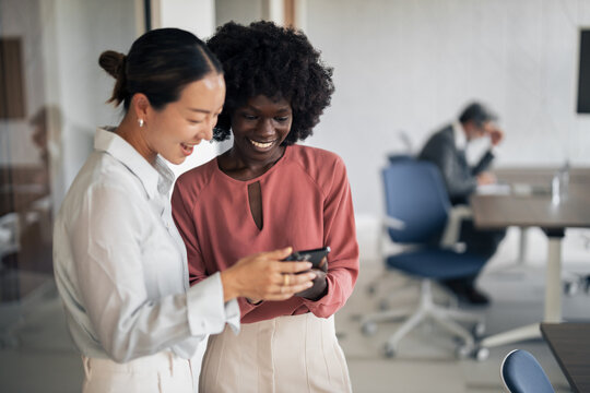 Diverse businesswomen collaborating and sharing content on smartphone - Powered by Adobe