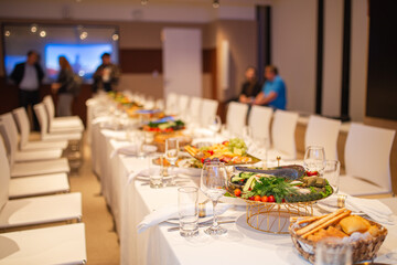 Wide shot of set table with buffet and guests at business event