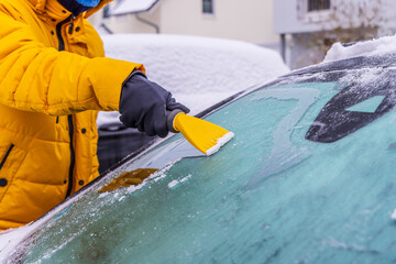 Removing snow and ice from car windshield.