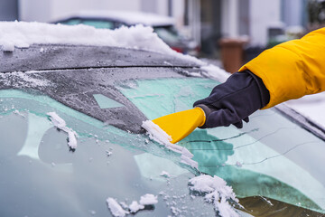 Removing snow and ice from car windshield.