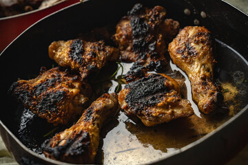 Roasted chicken drumsticks and thighs in pan with rosemary