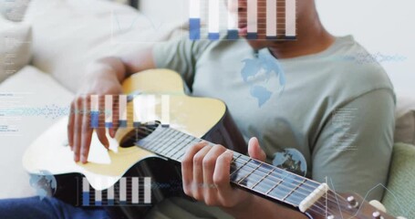Man strumming guitar on sofa, activating bar charts, globe icon and code lines for music analytics