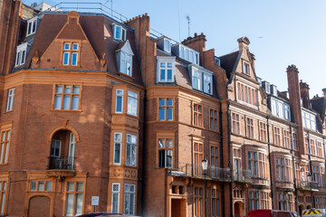 Fototapeta premium Stroll along Hans Crescent with elegant red brick townhouses and vibrant city life Knightsbrigde in London
