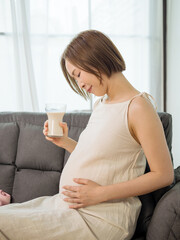 Asian pregnant woman drinking milk for the health of herself and her unborn baby.