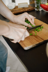 Unrecognizable woman chopping cilantro on cutting board