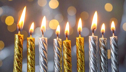 Row of lit Hanukkah candles with bokeh background.