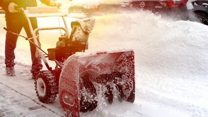 A man with a snow blower removes snow on the street