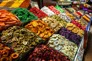 Various types of colorful dried fruits including kiwi oranges and apples displayed in a market