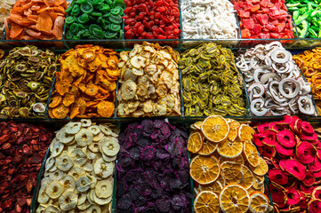 Various types of colorful dried fruits including kiwi oranges and apples displayed in a market