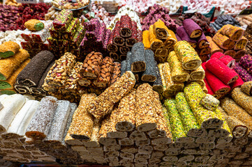 Various types of traditional Turkish delight lokum with nuts and flower petals displayed in a shop