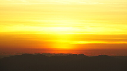 Fototapeta premium Golden sunrise over mountain silhouettes with warm sky 