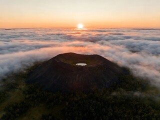 Aerial view of a volcanic crater above a sea of clouds at sunrise