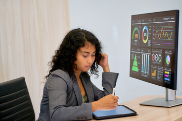 Mixed color businesswoman working with tablet and information graph on monitor for idea business.