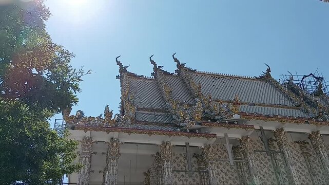 Close-up of a Buddha statue outside the main ordination hall (Ubosot) in a Thai temple, showing golden details, traditional architecture, and serene outdoor atmosphere