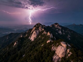 A dramatic lightning strike illuminates a mountainous landscape at dusk, highlighting rocky peaks and dense forest under a stormy sky.