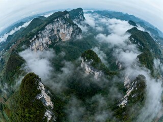 Aerial view of mist-covered mountain peaks and dense forests in a dramatic landscape