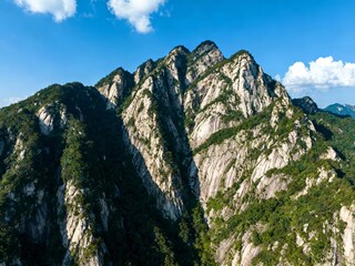 Aerial view of rugged mountain peaks covered in green vegetation under a clear blue sky