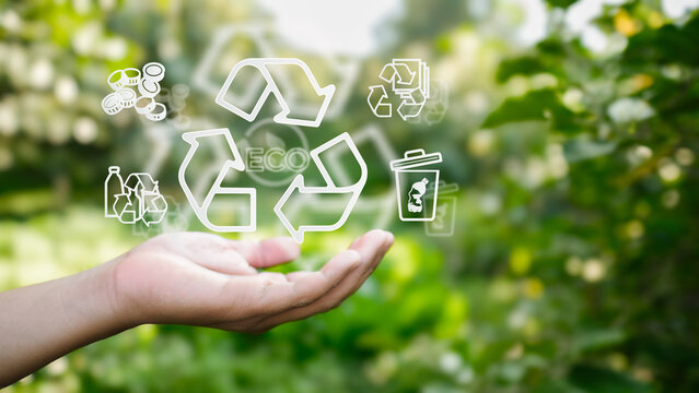 Human hand holding virtual recycle icons in green nature. Concept for circular economy, waste management, environmental care and eco-friendly.