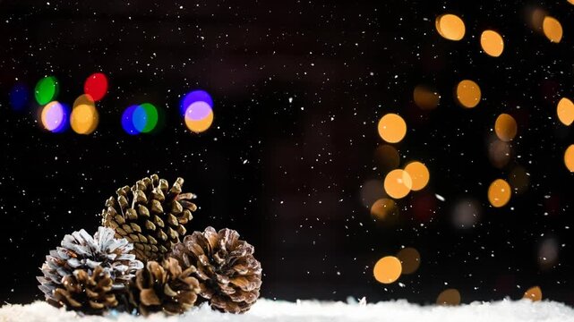 Animation of glowing lights and snow falling over christmas pone cones