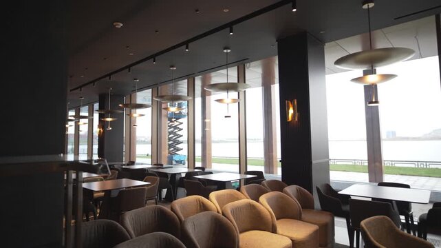 Zoned hotel cafeteria combines panoramic windows and chandeliers with muted lighting. Carefully divided space offers privacy openness