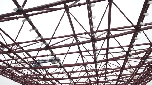 Process of installing metal structural frame shows active construction stage with visible beams joints. Scene feels technical and dynamic