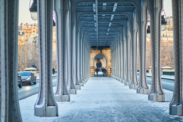 Perspective view of the Bir-Hakeim bridge in Paris during winter, with snow covering the walkway...