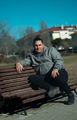 Fototapeta premium Young man relaxing on park bench enjoying solitude