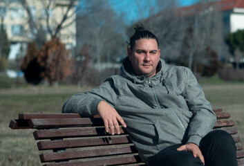 Fototapeta premium Man with man bun relaxing on park bench