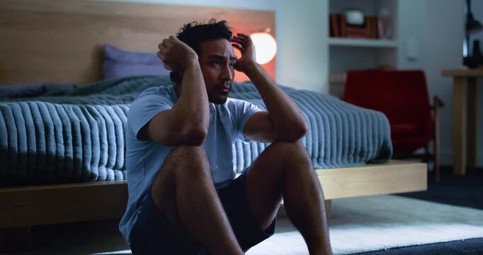 Sad, man and thinking in bedroom, night and stress for financial crisis, frustrated or mental health. Emotional, reflection and anxiety for job loss in home, late and person with depression and debt