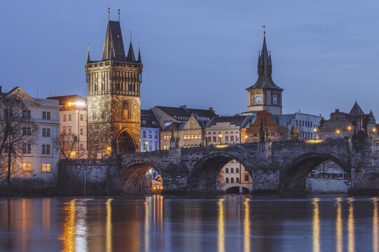 View of the Charles Bridge and Old Town Bridge Tower reflecting in the Vltava River under the soft glow of twilight, Prague, Prague, Czechia.