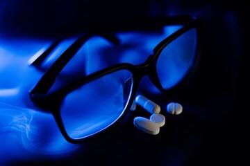 Niebieski dym na czarnym tle, okulary i tabletki © rychu.pl