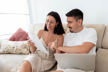 Young happy couple managing personal finance at home. Reviewing documents. Making plans. Planning...