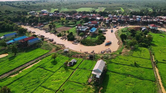 Aerial view of kampong phluk, a traditional floating village with stilt houses on the tonle sap lake in cambodia during a golden sunset.