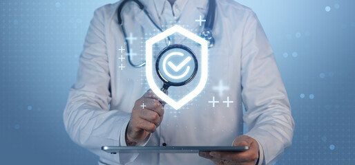 Doctor holding tablet with holographic insurance checkmark symbol representing healthcare security concept on a digital blue background.