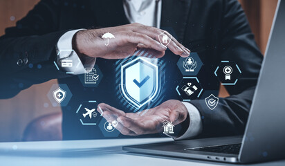 Businessman holding holographic shield with insurance and protection icons around it in futuristic digital interface concept on office background.
