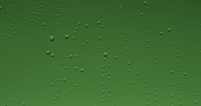 Close up of wet glass with dripping water drops and streaks of rain, on a bright green chroma key background, perfect for visual effects and background replacement. Slow motion.