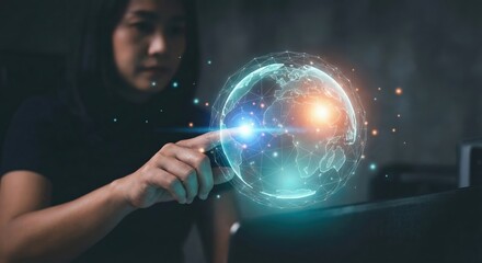 Adult Asian woman touching a digital glowing globe hologram indoors, symbolizing global connectivity and network technology with a positive smile in a dark environment.