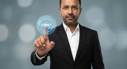 Indian adult man in a professional black suit indoors touching a digital start button on a virtual interface with a positive and focused mood, concept of business growth and innovation.