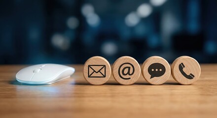 Contact us concept with wooden communication icons and computer mouse on a desk in an indoor office. This professional setup represents customer service and support during business hours.
