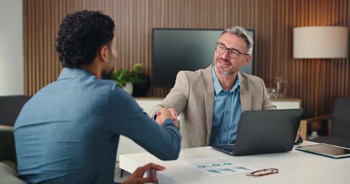 Corporate, men and meeting with handshake in office for partnership, agreement and finance deal. People, team and shaking hands with laptop for financial achievement, negotiation and funding proposal