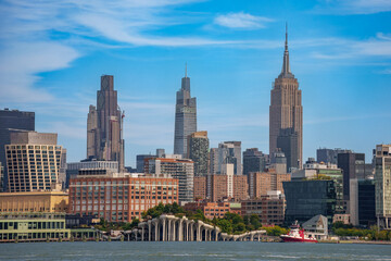Obraz premium Panoramic view of the Midtown Manhattan skyline featuring the Empire State Building and Little Island park at Pier 55 from the Hudson River, New York City.