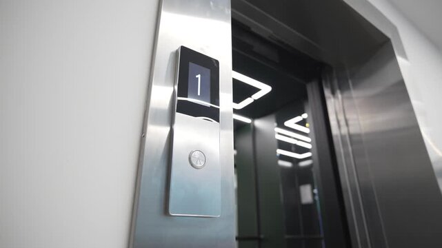 Digital screen above elevator call button shows floor position providing clear navigation information. Interface feels simple and readable