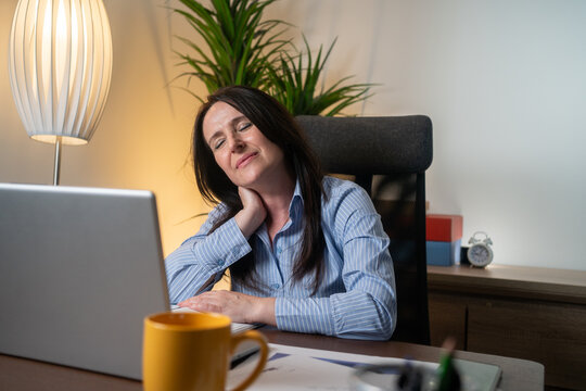 Tired business woman with neck pain looking uncomfortable while working with computer in the office.
