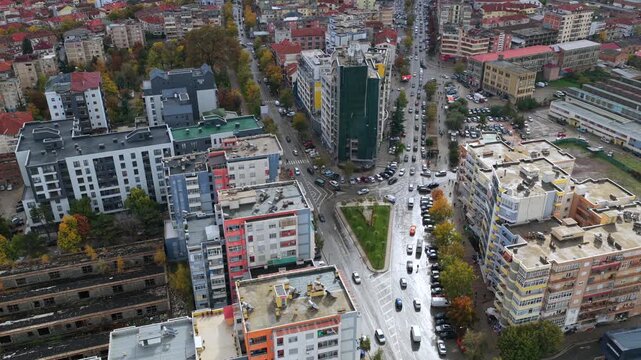 Autumn aerial video of Kor&ccedil;&euml; showcasing modern residential blocks, busy streets and dense city neighbourhoods beneath nearby mountains.