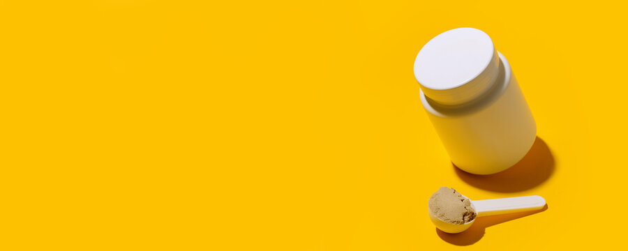 Scoop of Whey protein powder. Sports nutrition. Fitness diet and food concept - whey and soy protein shake powder, collagen on bright yellow background, copy space, banner, flyer