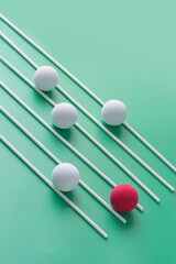 Abstract competition concepts still life with shapes. One red sphere leading other white spheres on green background.